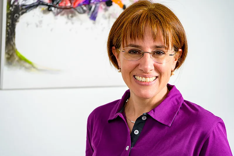 Zahnärztin Dr. med. dent. Monika Blum lächelt in ihrer Praxis
